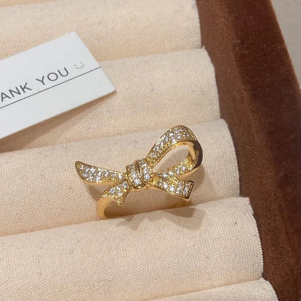 Gold miniature zircon inlaid bowknot ear stud and matching ring set on display