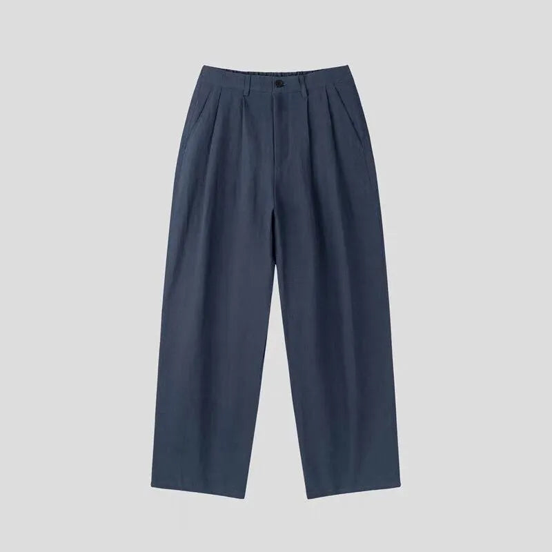 Men's apricot coloured wide-leg cotton linen trousers with a mid waist and zip fly on a neutral background.