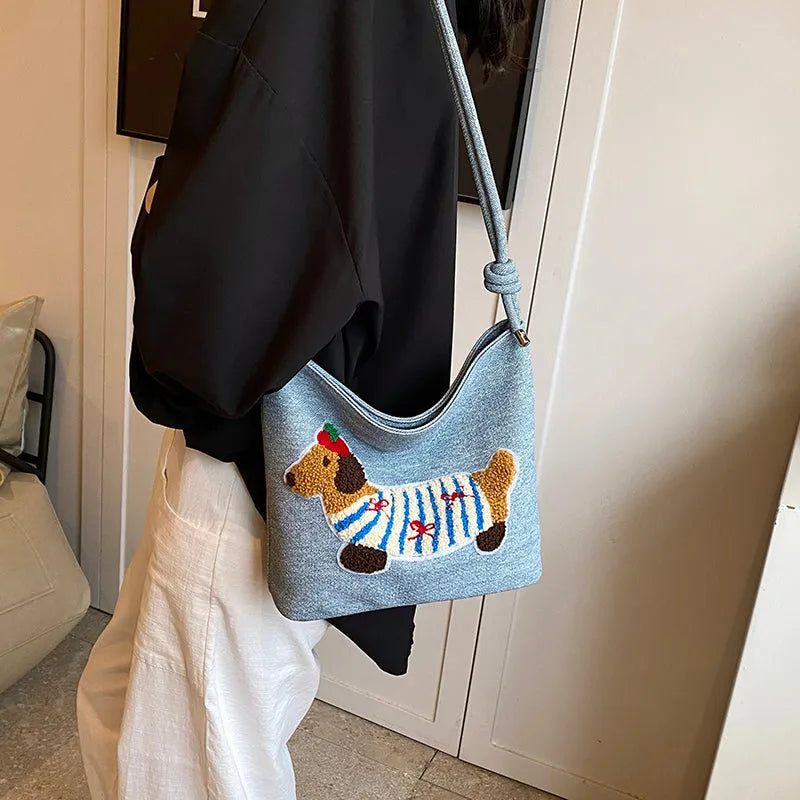 Cartoon sausage dog bucket bag in polyester with canvas lining, soft crossbody shape and single strap.