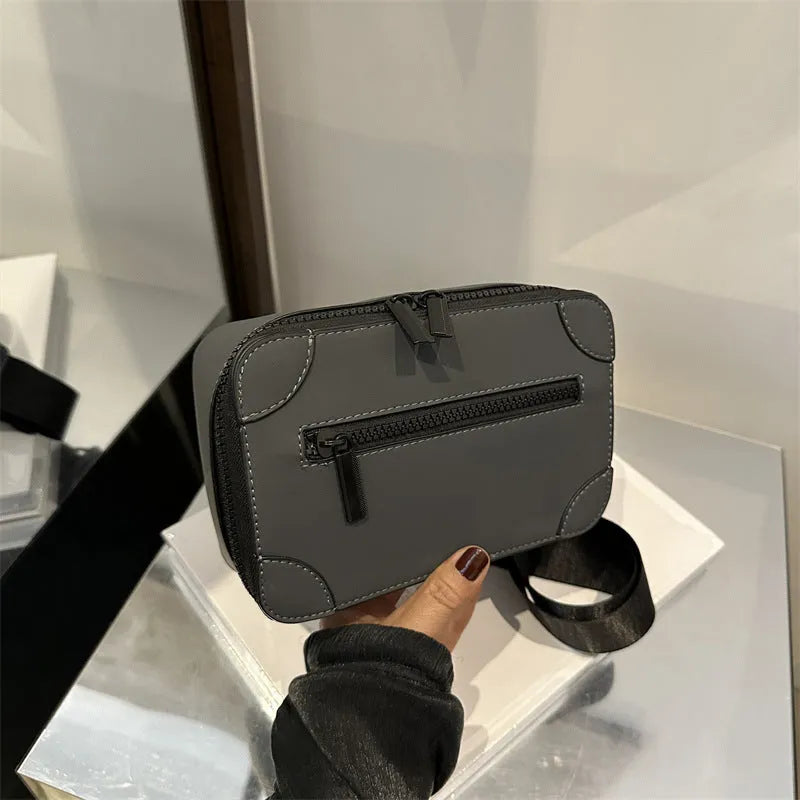 A small, square, structured crossbody bag in a choice of colours, showing its horizontal shape and sewing line detailing.