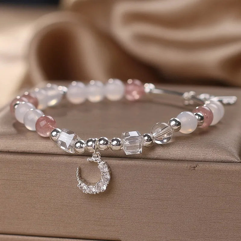 Natural strawberry quartz bracelet with pink cube sugar beads and moon pendant on a flat surface