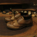 Men's light brown leather lace-up shoes with hand-distressed carving detail on the upper and a round toe.