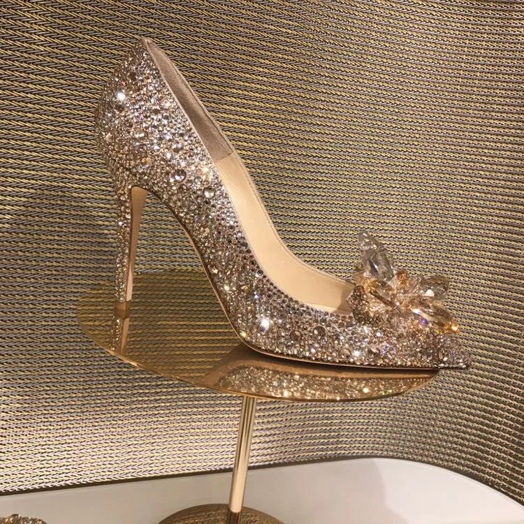 Gold women's stiletto heels with sequin upper, rhinestones, a bow, and a pointed toe.