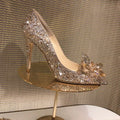 Gold women's stiletto heels with sequin upper, rhinestones, a bow, and a pointed toe.