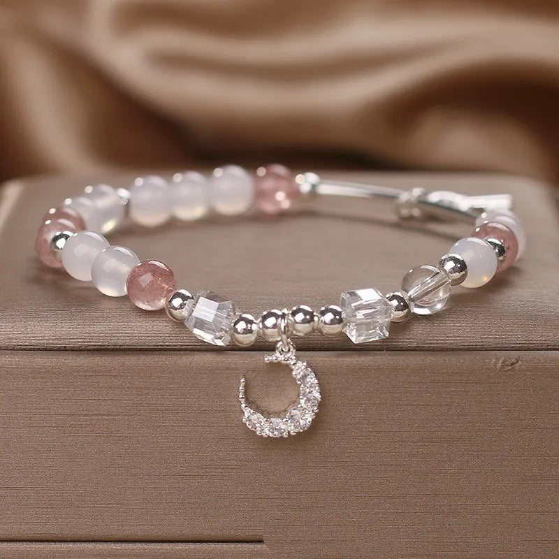Natural strawberry quartz bracelet with pink cube sugar beads and moon pendant on a flat surface