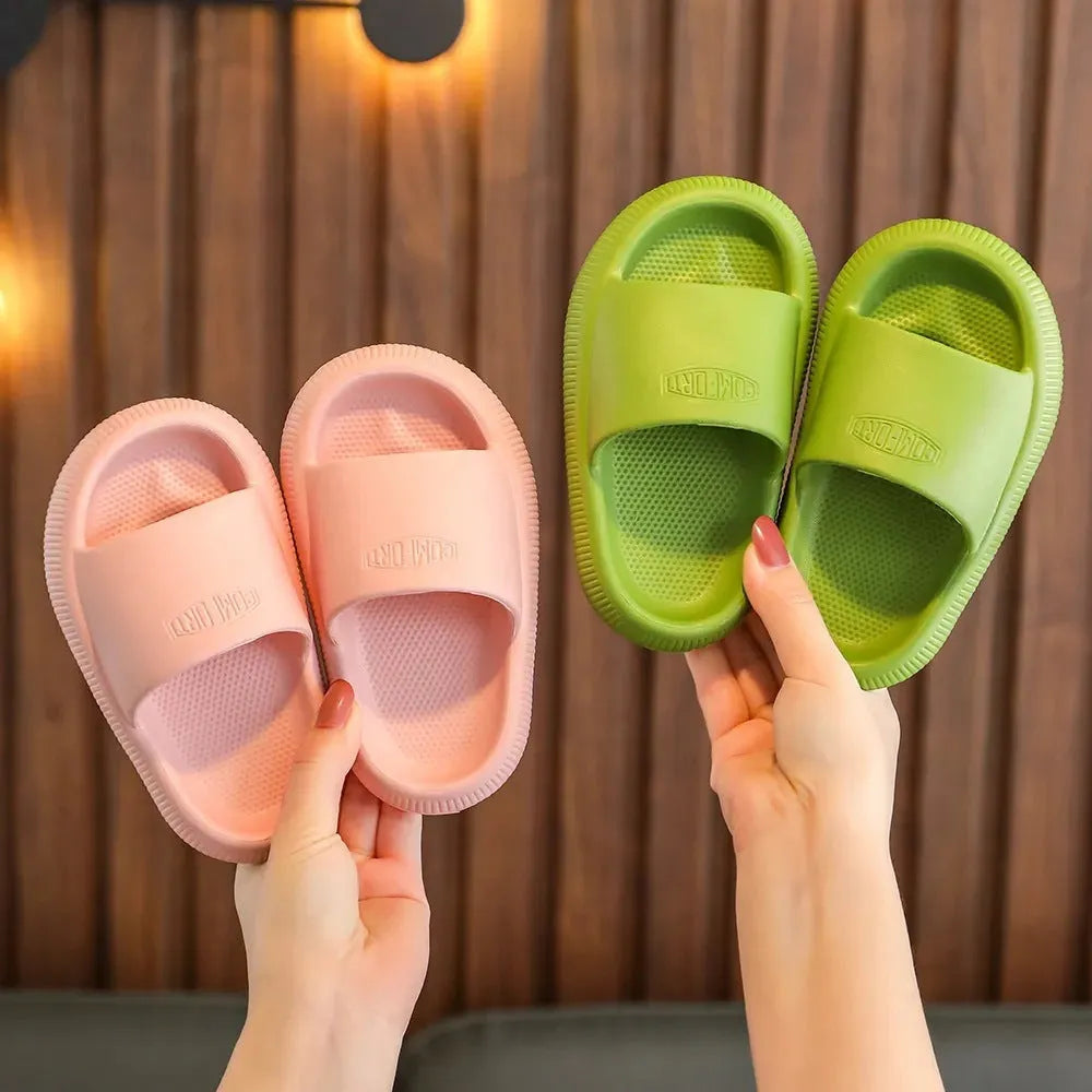A pair of bright blue, one-piece EVA children's slippers with a textured non-slip sole, shown on a wooden floor.