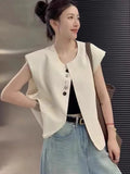 Women's loose fit sleeveless vest in beige and black, showing V-neck and pocket detail.