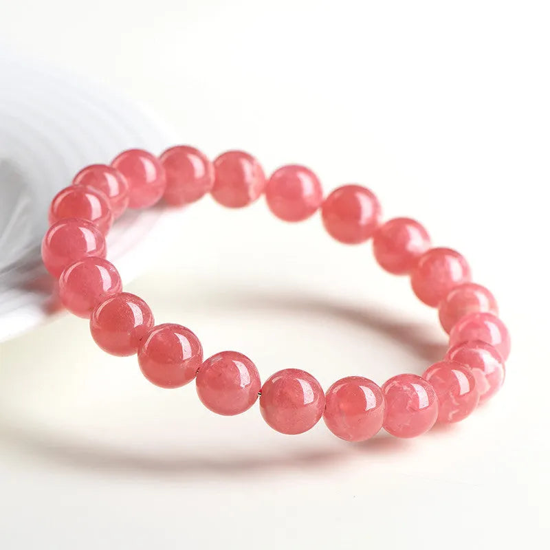 Women's geometric rhodochrosite crystal bracelet with a longevity lock clasp on a wrist.