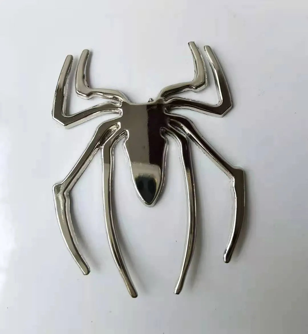 Three-dimensional metal spider bumper sticker in gold colour on vehicle surface