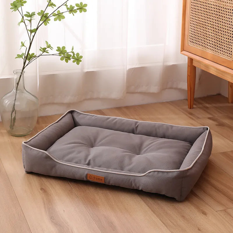 Grey waterproof dog sofa bed with raised edges on wooden floor