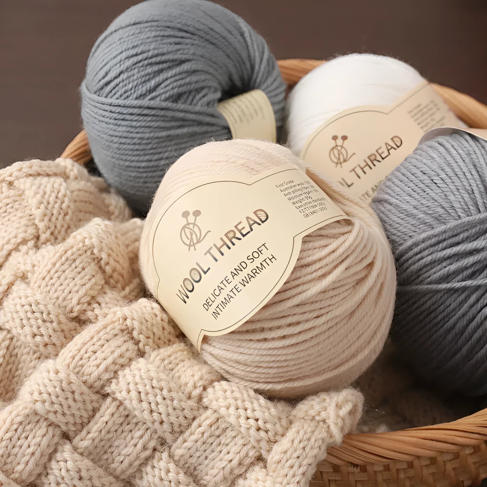 One roll of fine, twisted woolen hand-knitting yarn in a colour from the available palette, shown next to knitting needles.