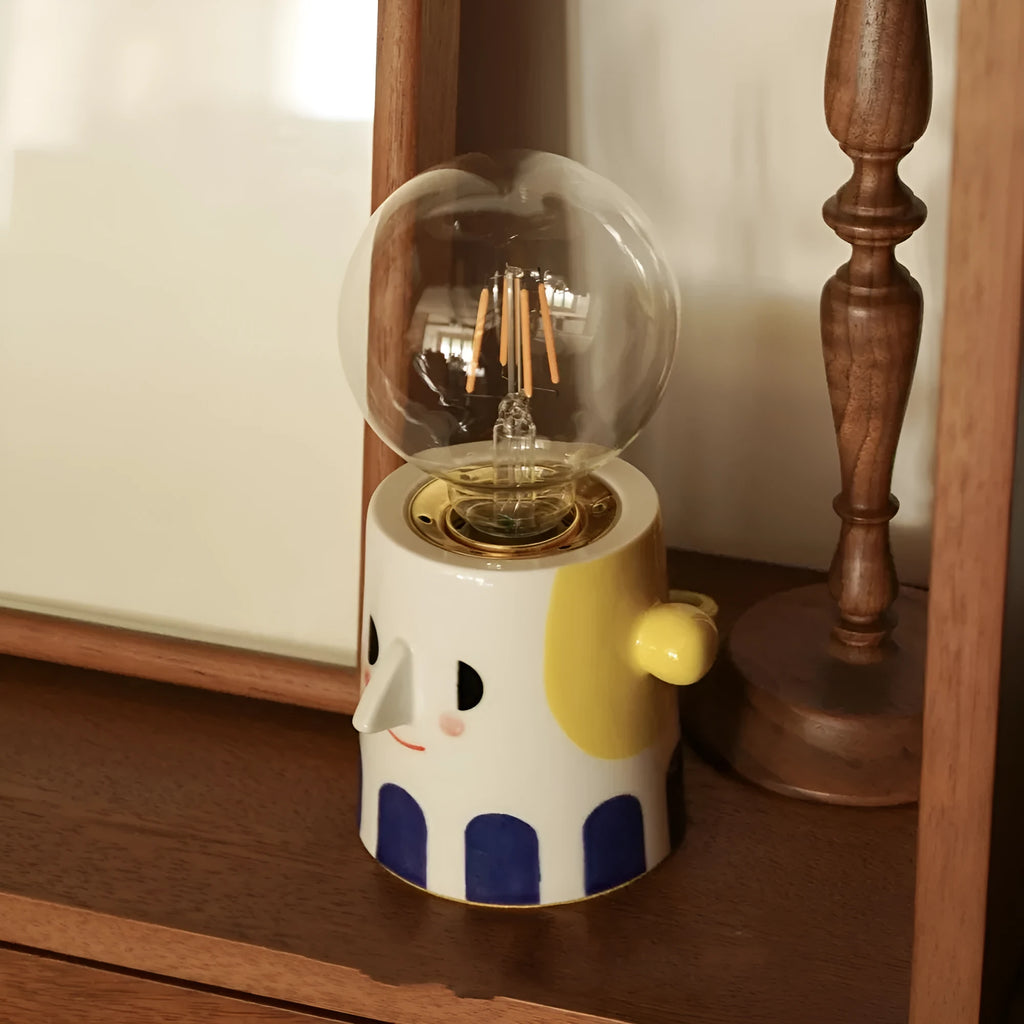 Handmade ceramic table lamp with white spherical shade on a wooden surface.