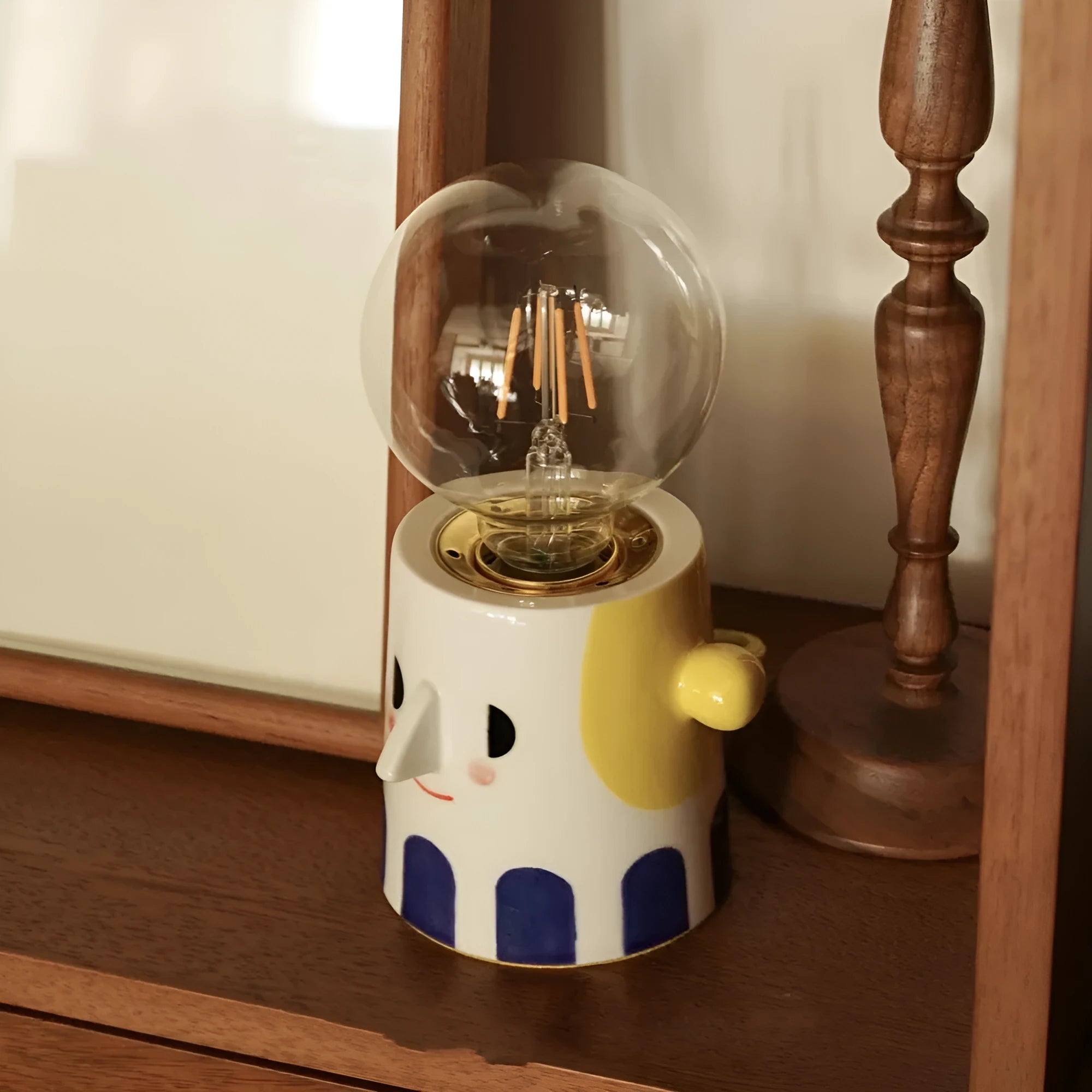 Handmade ceramic table lamp with white spherical shade on a wooden surface.