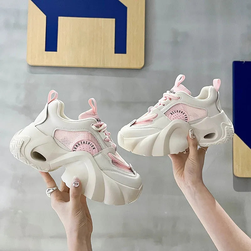 Women's beige sneakers with a thick sole, cross shoulder straps, and a mid heel.