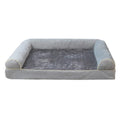A square grey dog bed with a raised sponge can border on a wooden floor.