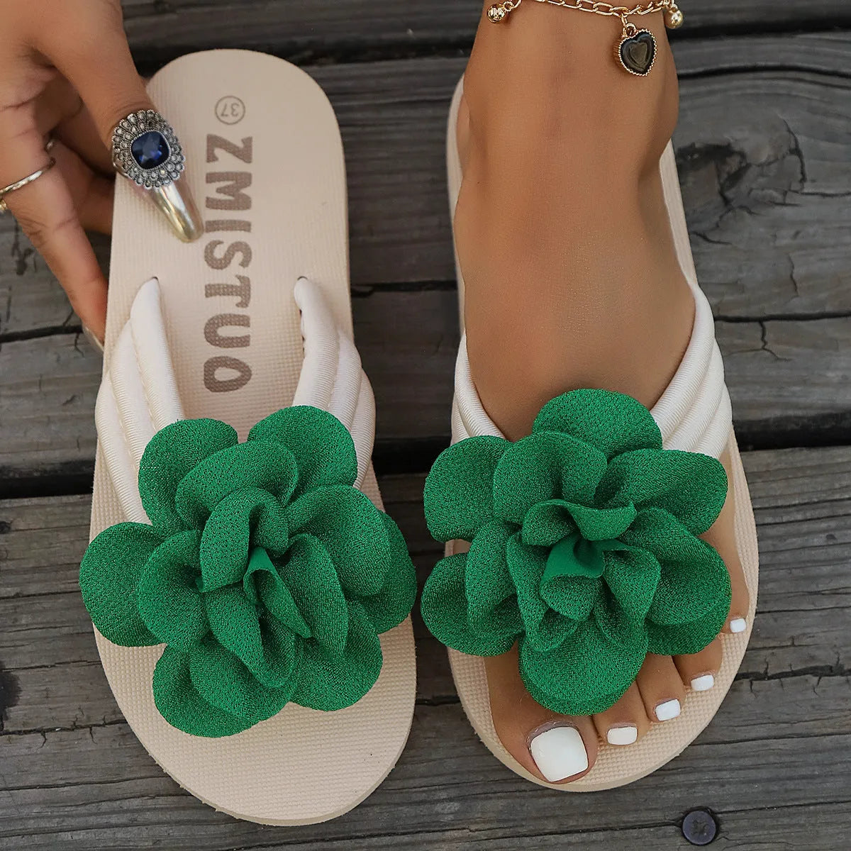A pair of solid colour flip flop slippers with a small flower detail on the PU upper.