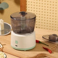 White mini electric meat grinder with transparent cup on kitchen countertop