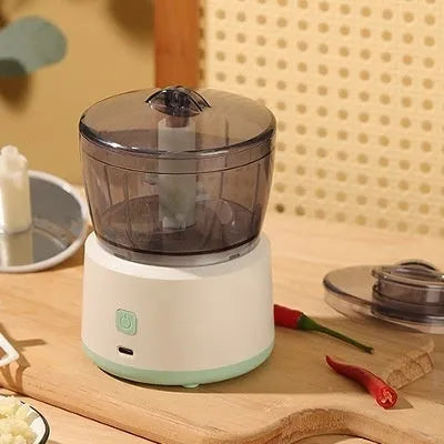 White mini electric meat grinder with transparent cup on kitchen countertop