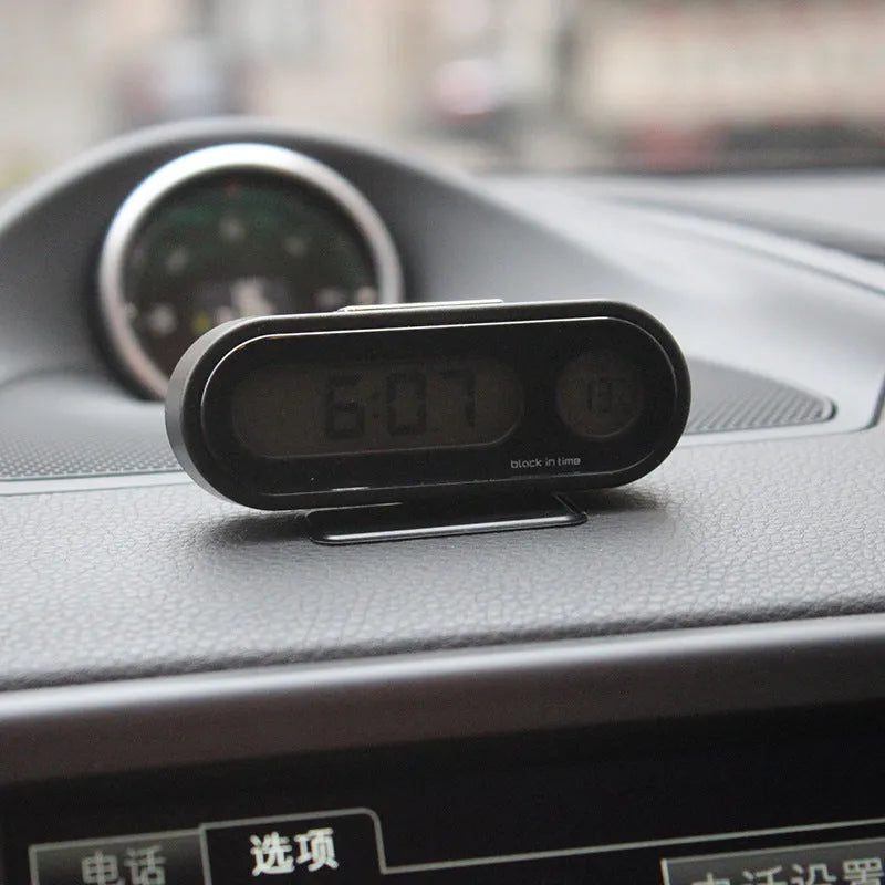 Black electronic car clock and thermometer with LED display on an adjustable bracket.