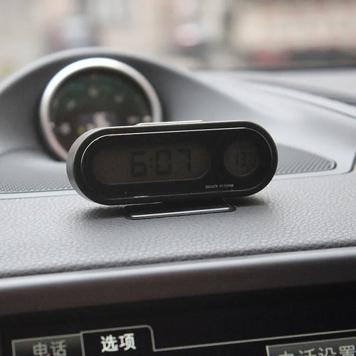 Black car digital clock thermometer with luminous display on adjustable bracket showing time and temperature