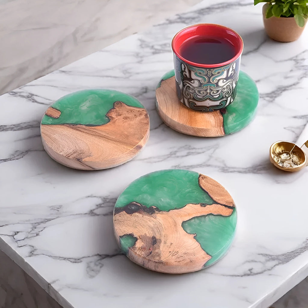 Round and square black and green resin coasters with wood texture for tea pots on a table.