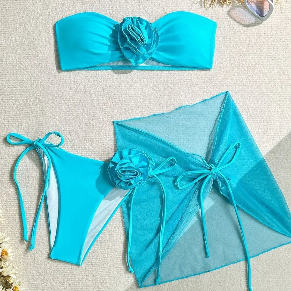 Women's pink swimsuit set with 3D flower tube top, high-waisted bottoms, and separate tie-front skirt laid flat.