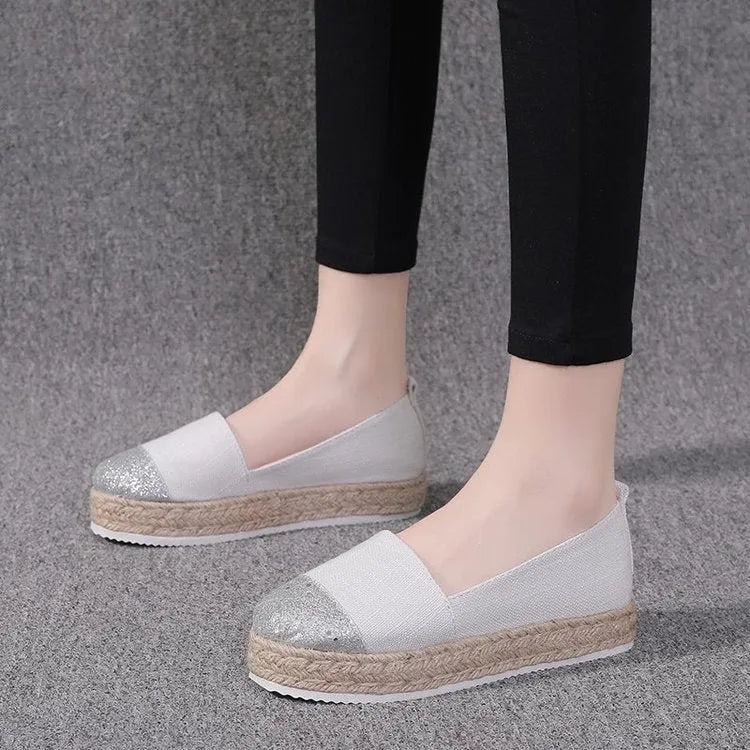 Beige and black women's canvas flat shoes with round toe and slip-on design.