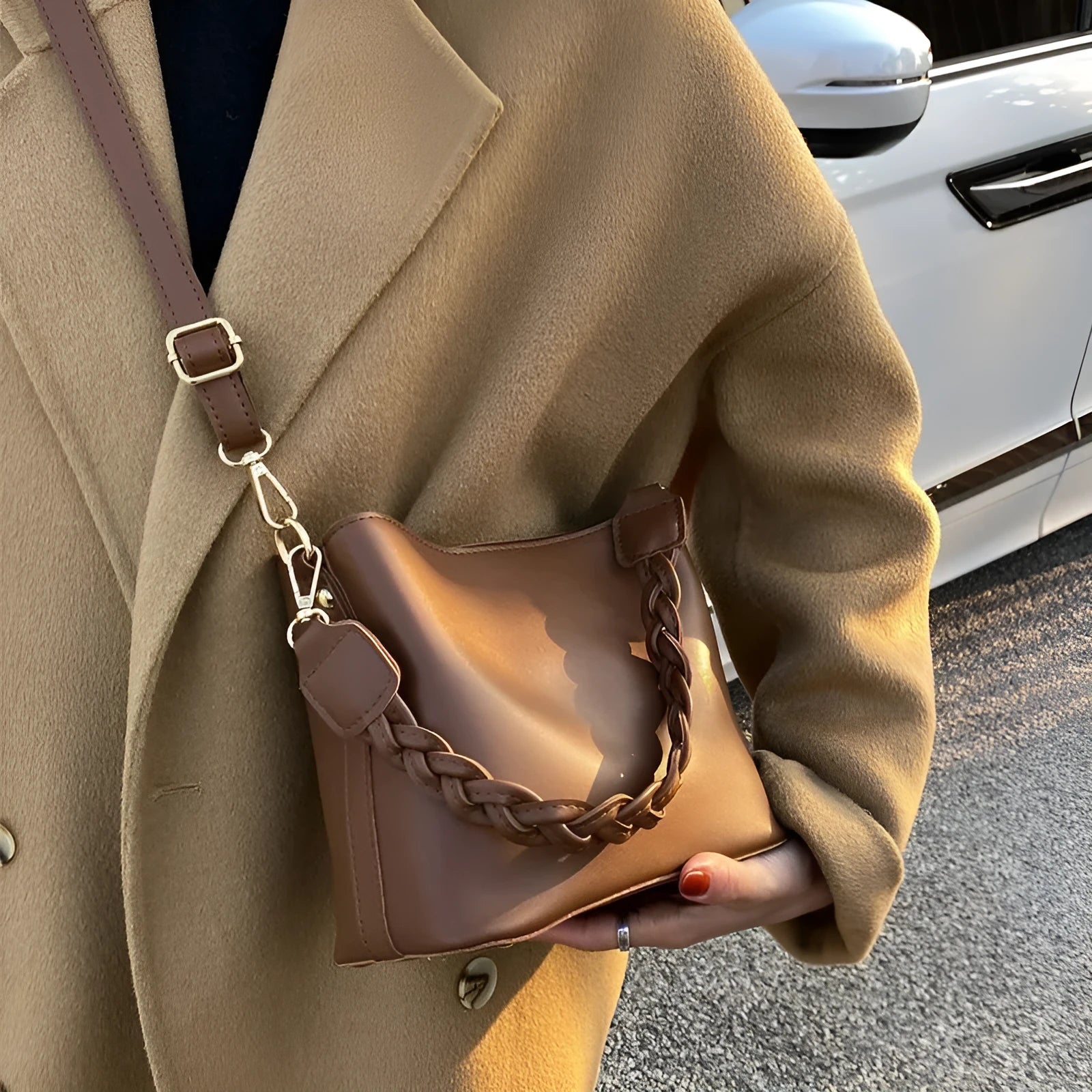 Khaki woven texture one-shoulder crossbody bucket bag with an underarm strap on a table.