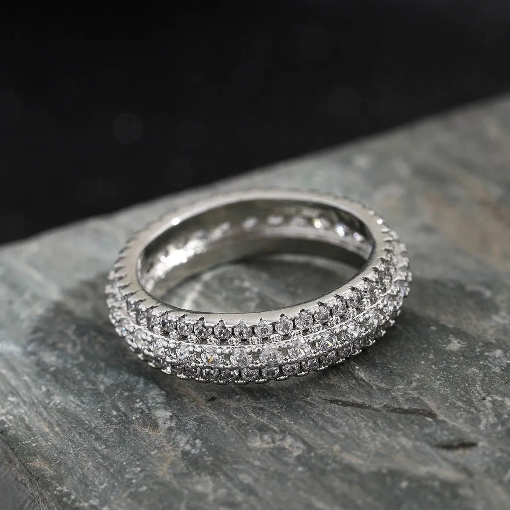 Geometric copper ring with a triangular zircon stone, shown in white gold finish on a finger.