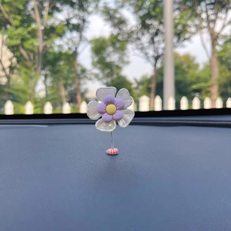 Small colourful plastic swing ornament for car dashboard, shown in blue, green, pink, purple, and yellow.