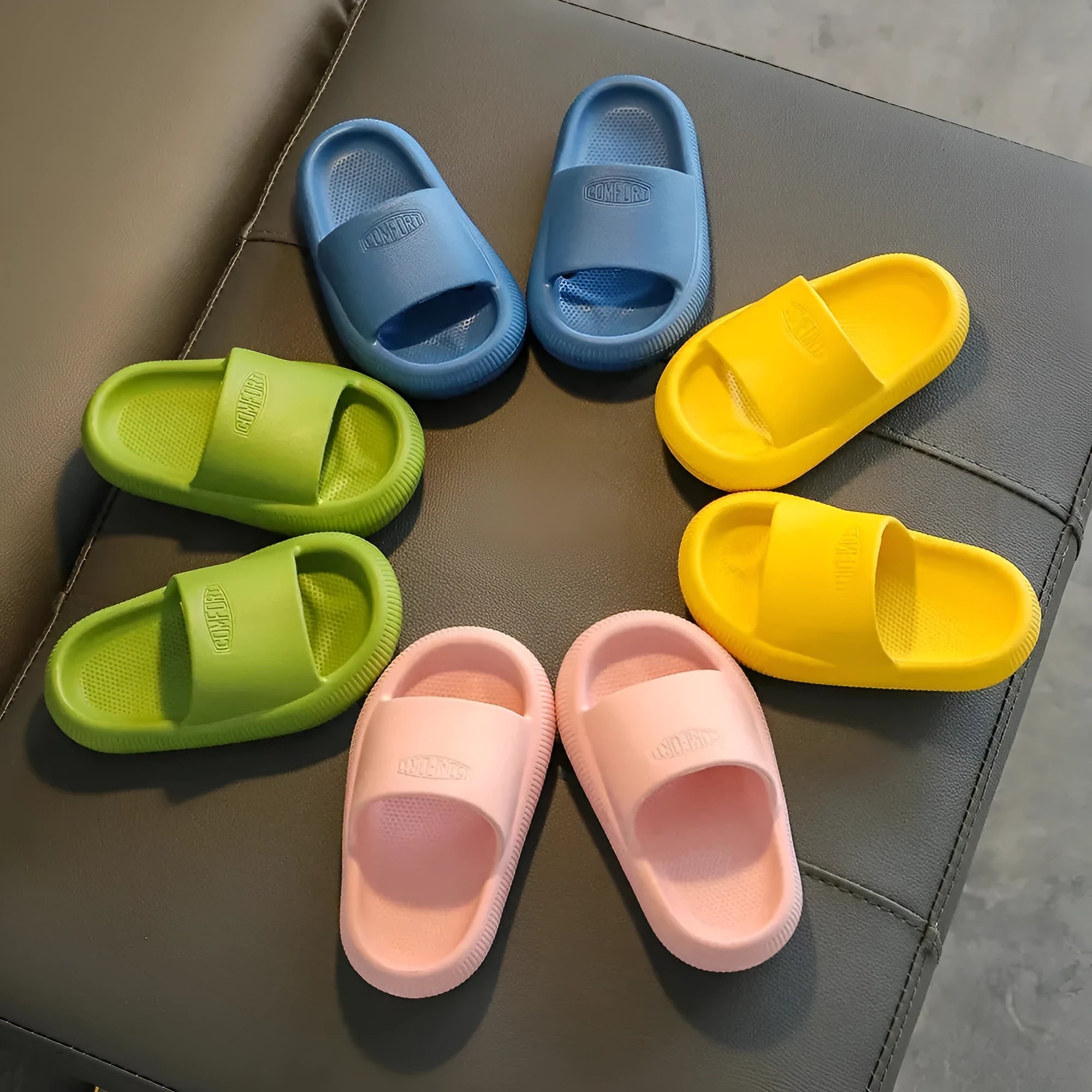 A pair of bright blue, one-piece EVA children's slippers with a textured non-slip sole, shown on a wooden floor.
