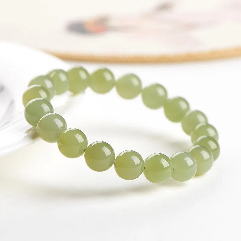 A polished Hetian jade bead bracelet in deep clear water colour on a wrist.