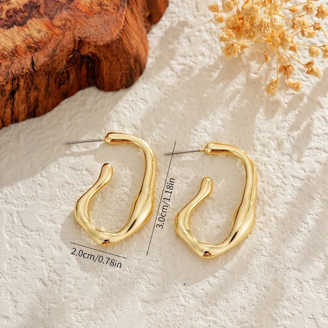 Gold irregular shaped minimalist drop earrings with abstract geometric design on neutral background