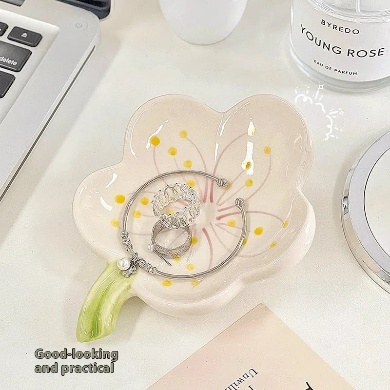 White porcelain scallop shell tray with optional warm LED night light, holding small jewellery on a bedside table.