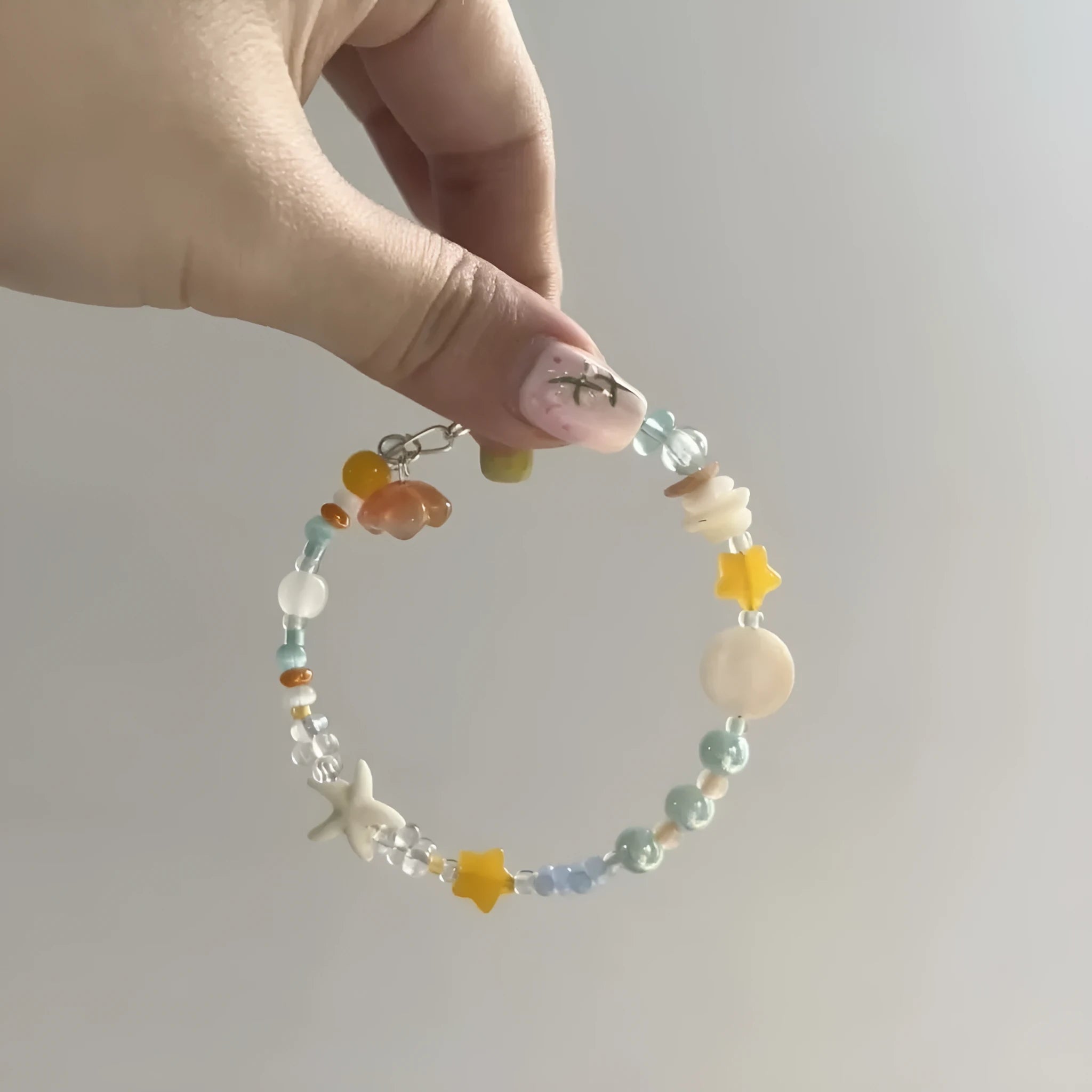 Orange sea colour summer bracelet with diamond shape and round mixed-material elements on wrist