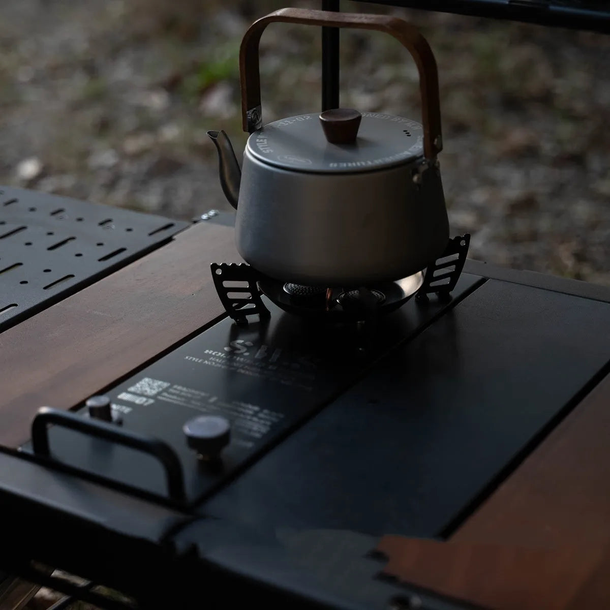 Black three-head split camping stove on outdoor table with burners visible