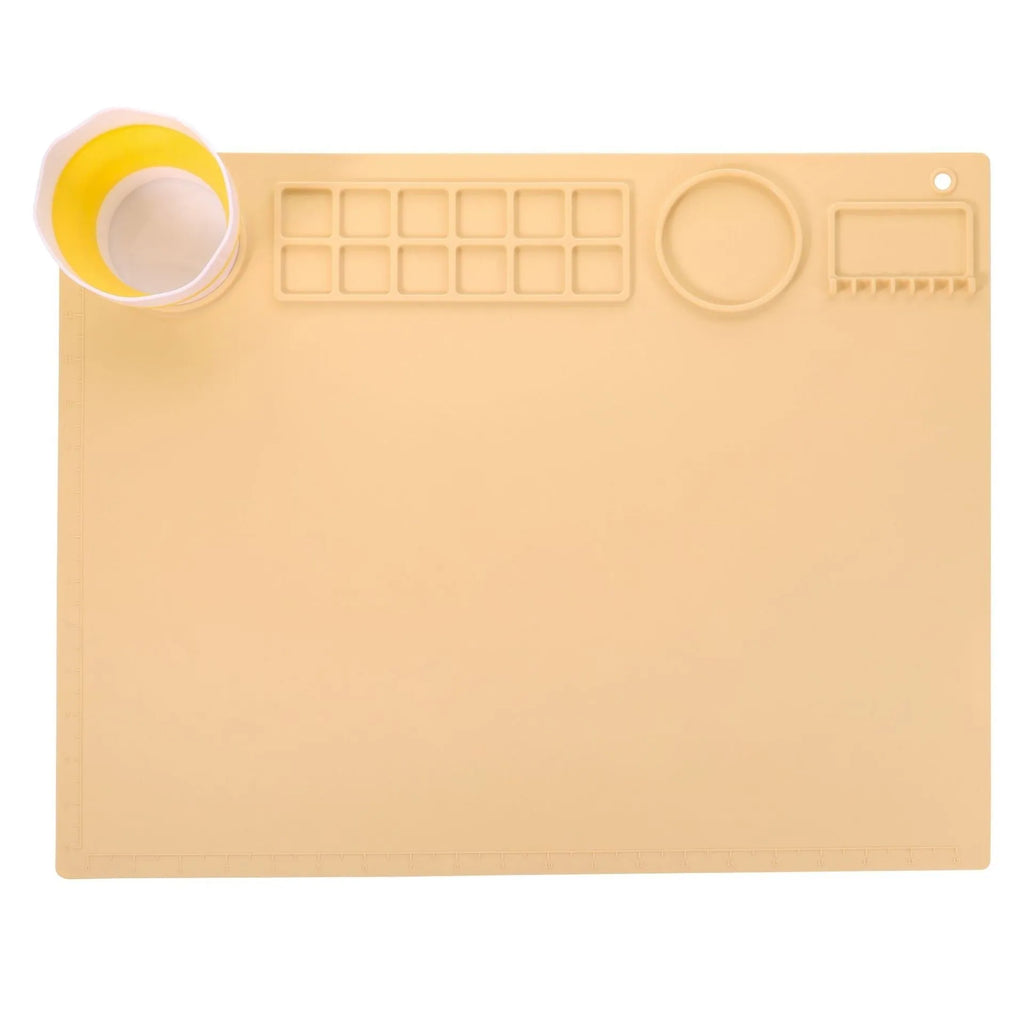 Light blue silicone painting mat with two round bowls, placed on a wooden table with paintbrushes.