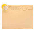 Light blue silicone painting mat with two round bowls, placed on a wooden table with paintbrushes.