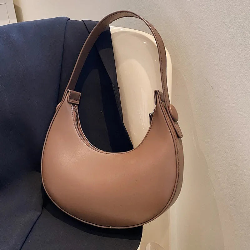 Retro-style dumpling-shaped PU leather shoulder bag in cream yellow showing front sandwich pocket.
