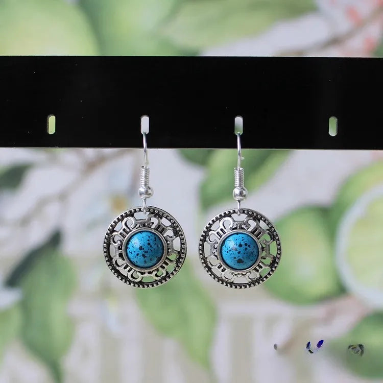 A pair of handmade geometric flower disk earrings in Tibetan silver and turquoise with ethnic patterns.