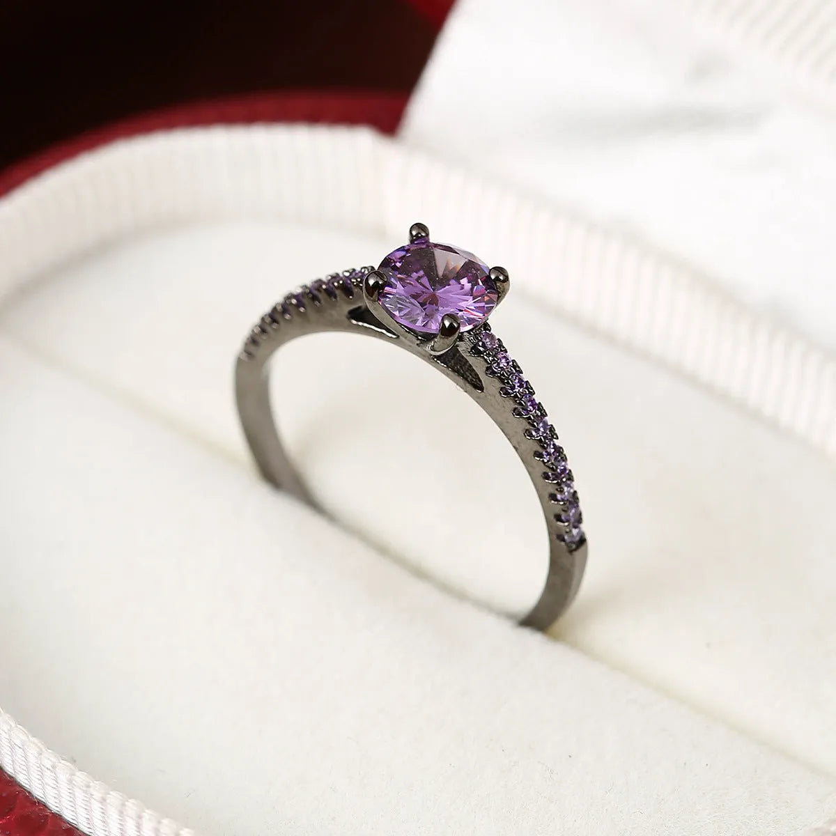 Close-up of a hexagonal geometric copper ring with a central zircon stone in a gun black and purple electroplated finish.
