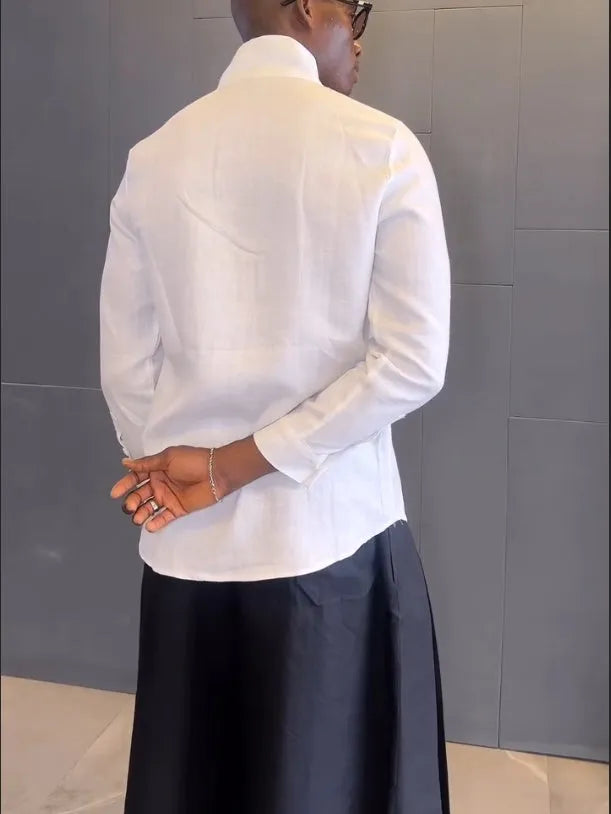 White asymmetrical shirt and black pleated trousers co-ordinate set laid flat