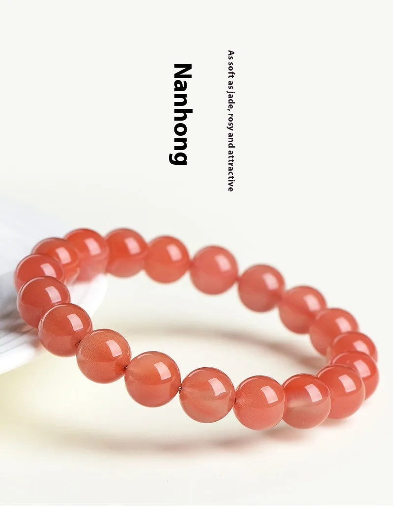 Natural cherry red agate bead bracelet with polished stones on a wrist, showing colour variation and secure clasp.