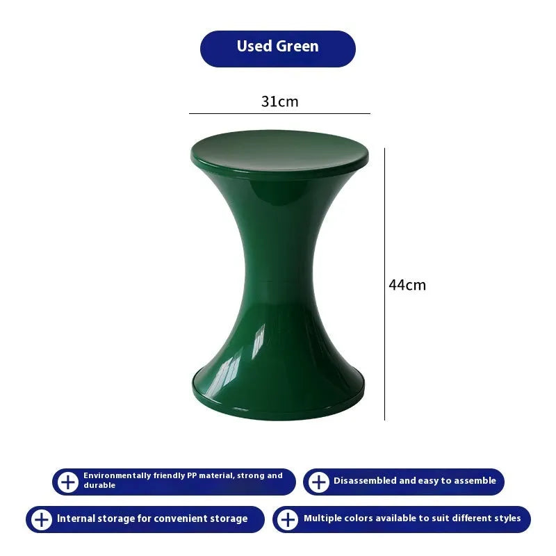 A green plastic hourglass-shaped shoe changing stool on a wooden floor.