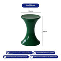 A green plastic hourglass-shaped shoe changing stool on a wooden floor.
