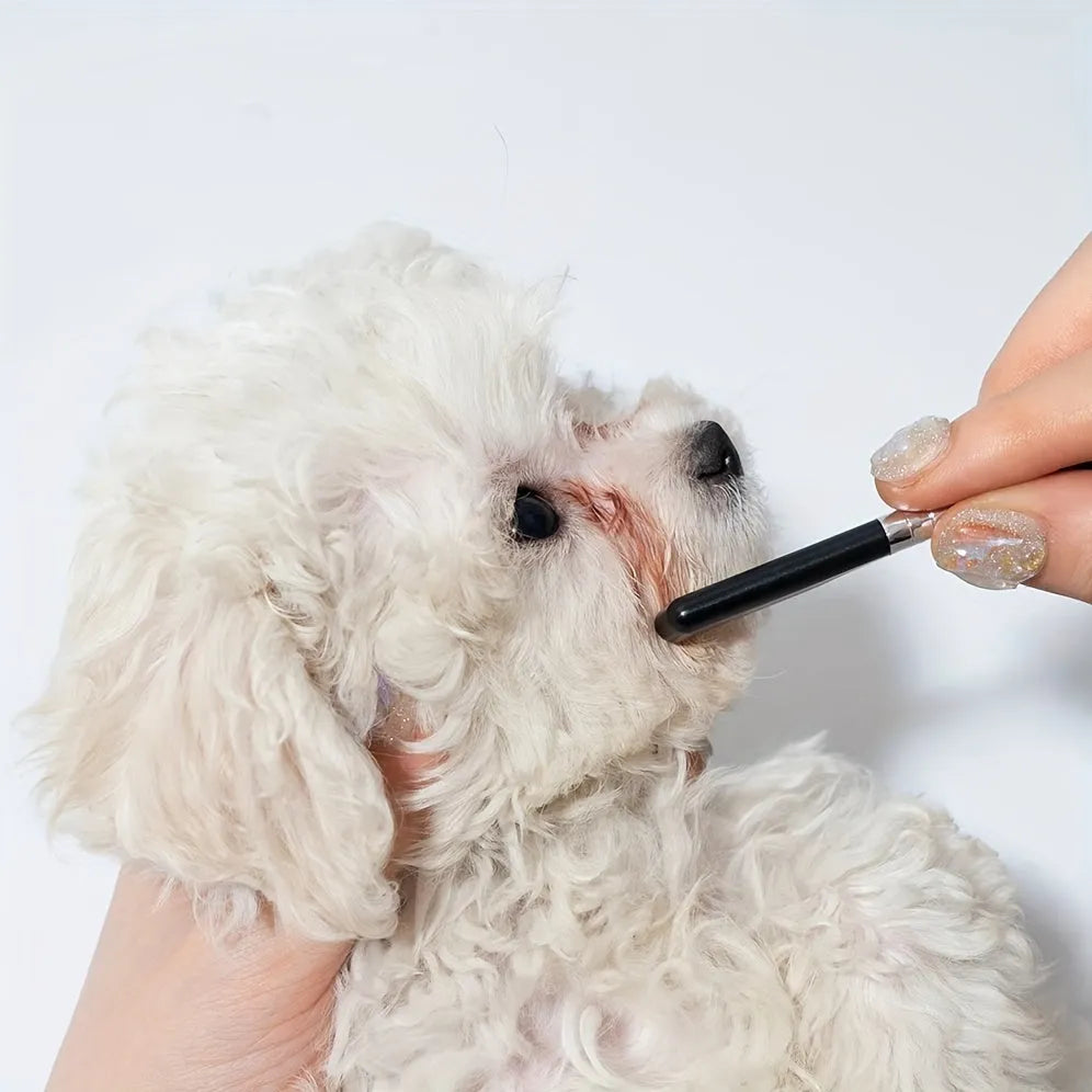 Black ambidextrous pet grooming brush with soft rubber bristles for gentle eye cleaning and hair removal on dogs and cats.