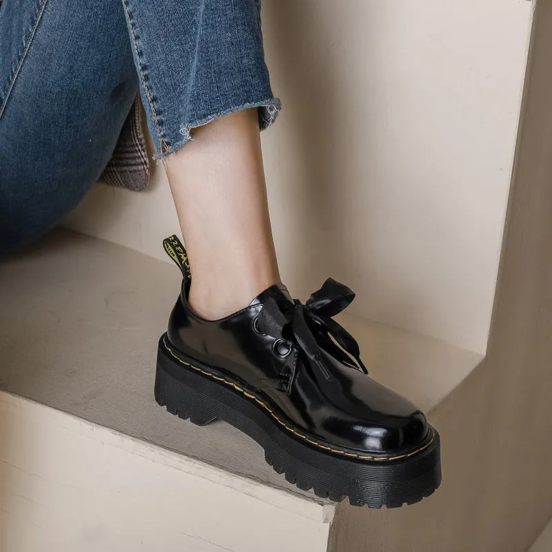 Black and white women's thick-soled leather shoes with ribbon cross straps and laces.