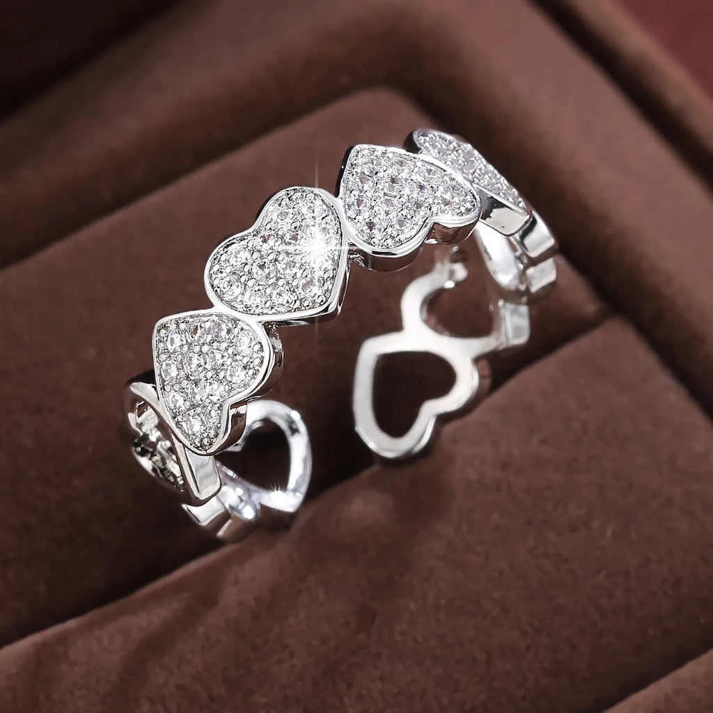 Geometric adjustable love heart ring with diamond-cut facets in gold tone on a wooden surface.