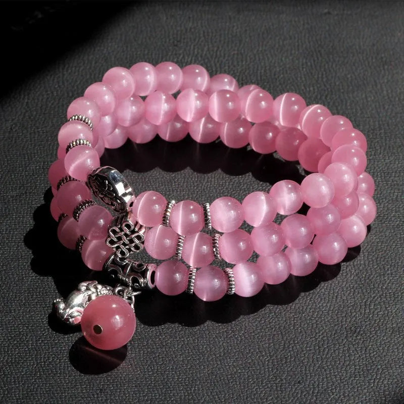 Women's opal bracelet with three interlocking rings, a Lucky Cat charm, and geometric stones in various colours.