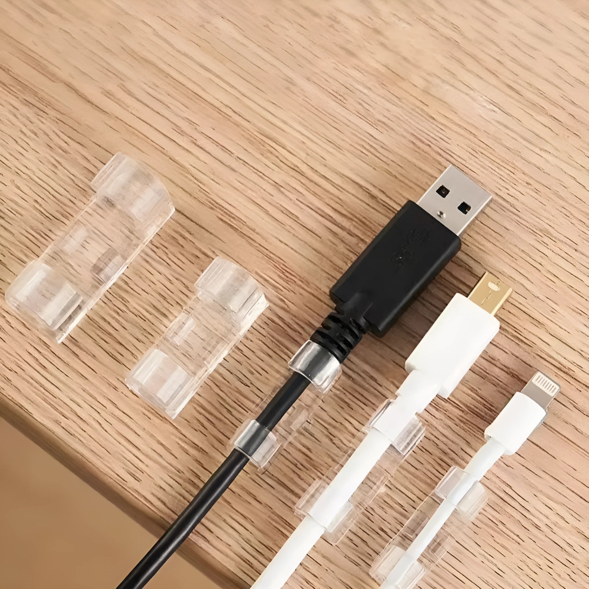 Transparent plastic self-adhesive cable management clips on a white background.